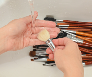 person washing makeup brushes